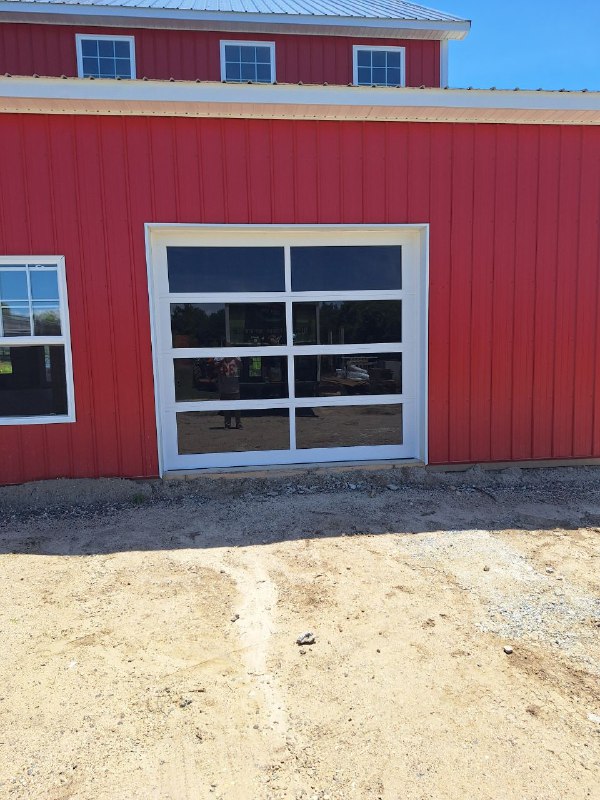 Red barn with a glass garage door and a small window.